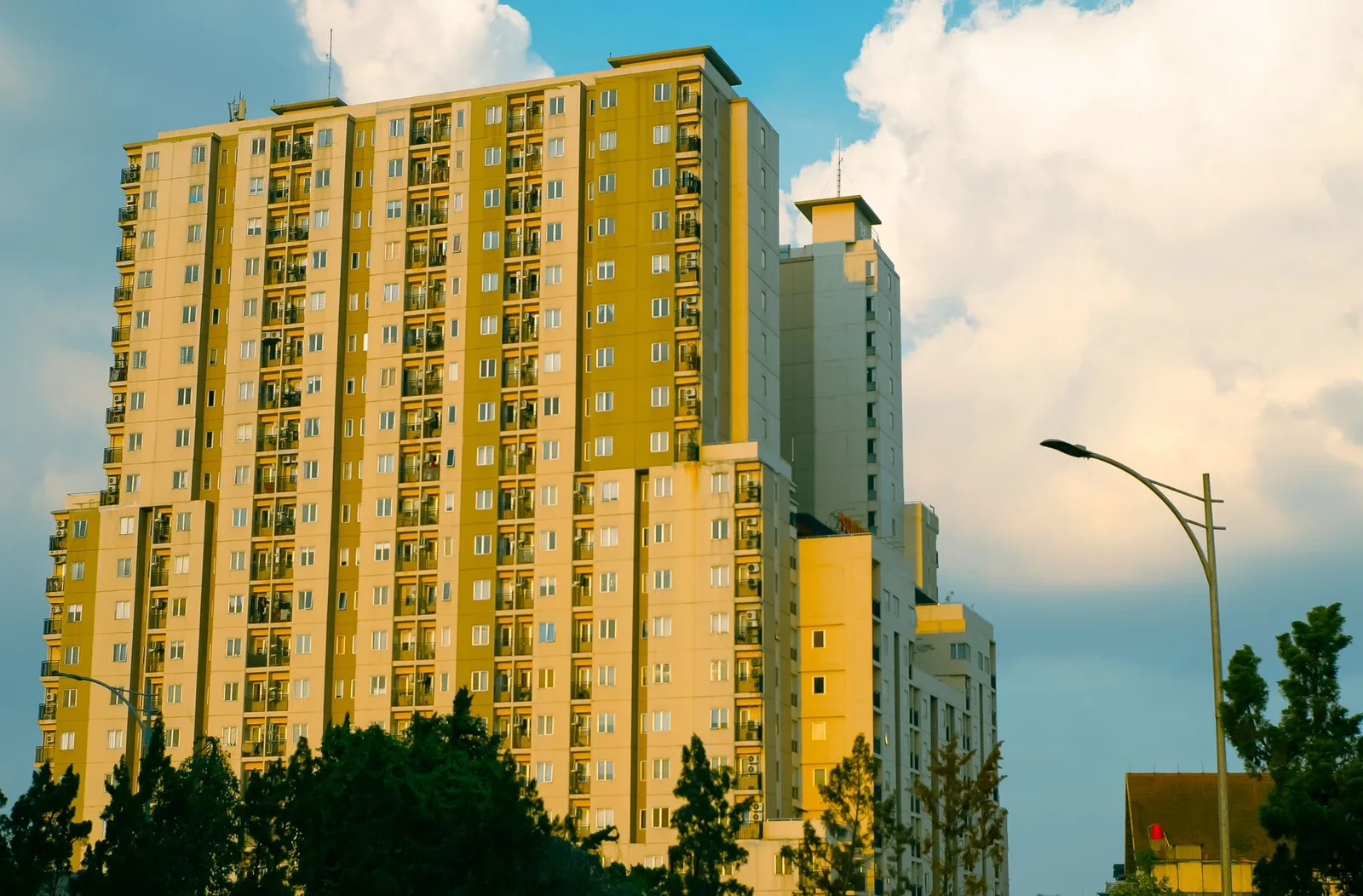 High-rise apartment building in Bandung, Indonesia, captured at sunset with dramatic clouds.