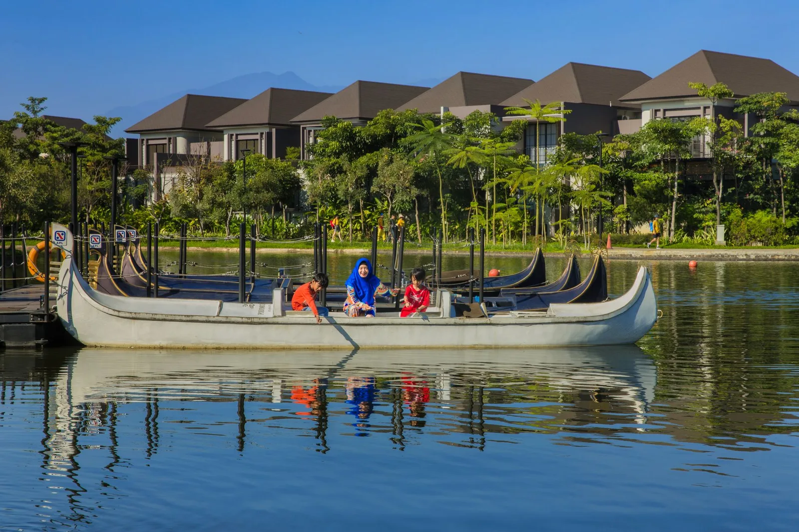 Relaxing boat ride on a serene lake in Bandung with modern villas and lush greenery.