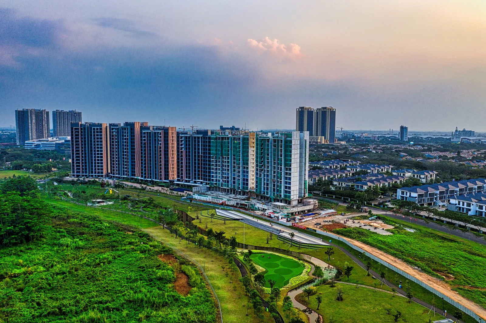 Drone shot capturing modern apartment buildings and green spaces in Banten, Indonesia at sunset.