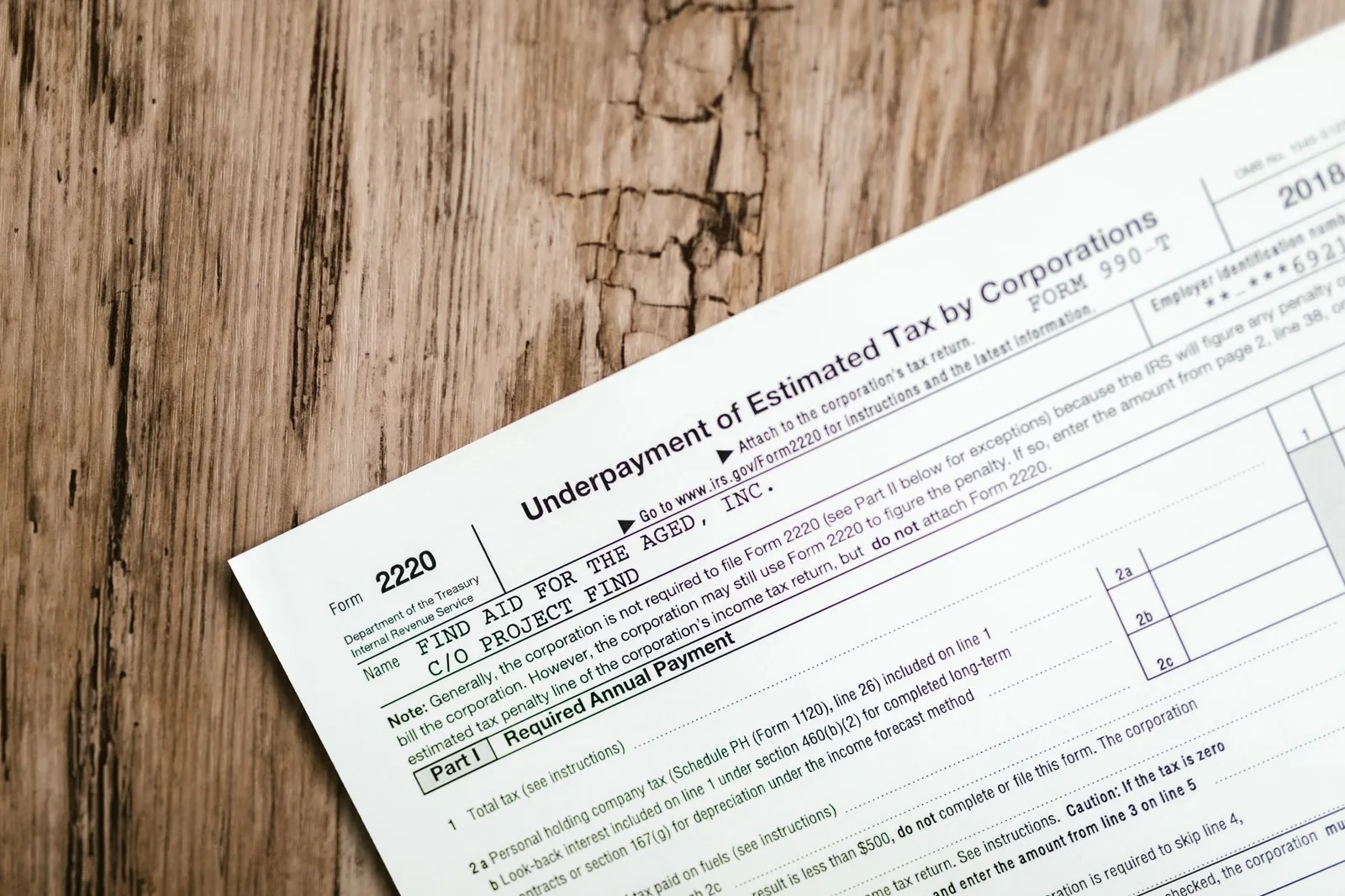 Close-up of a corporate tax form on a textured wooden surface, highlighting document details.