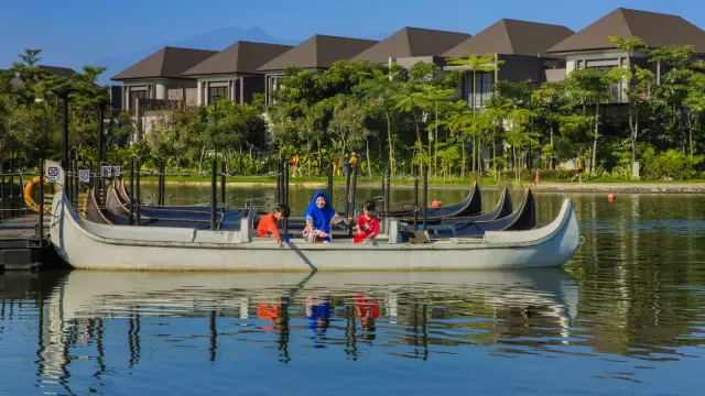 Relaxing boat ride on a serene lake in Bandung with modern villas and lush greenery.