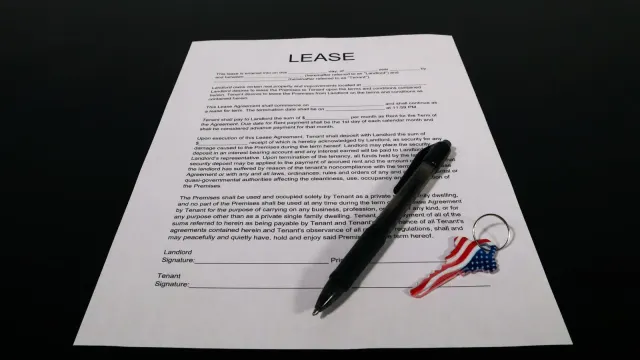 Lease agreement document with pen and American flag keychain on a black table.